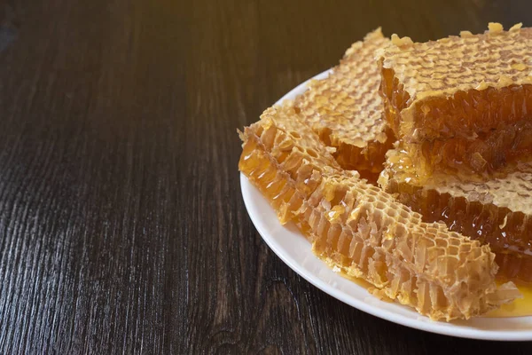 Mézes fésűk fehér tányérral a fa asztalon. Természetes organikus méhészeti termék. Egészséges életmód. Másold le az SMS-ed helyét. Közelkép fénykép. — Stock Fotó