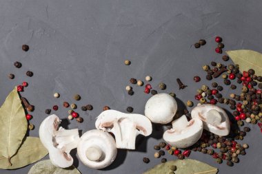 Siyah taş arka planda mantar ve baharatlar. Siyah, kırmızı, beyaz biber, defne yaprağı ve karanfil. Dilimlenmiş mantar. Kopyalama alanı, üst görünüm, yakın çekim fotoğraf. 