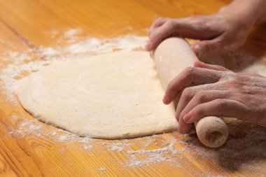 Merdaneli eller pizza için hamur yapar. İtalyan pizzası hazırlama süreci ahşap masada. Pizza hamuru