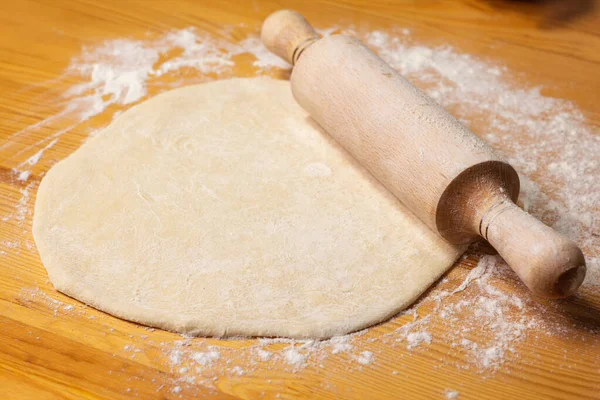 Pizza dough on wooden background. Rolling-pin and flour. Selective focus — Stock Photo, Image