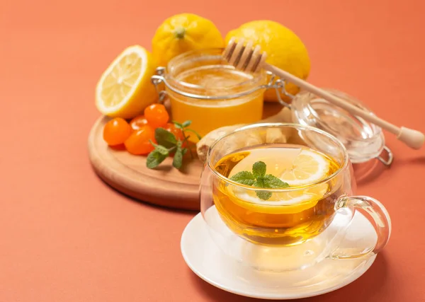 민트와 레몬을 곁들인 생강차. 건강하고 뜨거운 음료. 꿀 항아리에 넣은 액체 꿀이야. 밝은 배경에 크리스탈 컵. 선택적 초점. — 스톡 사진