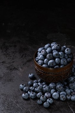 Siyah arka plandaki kasede taze, sulu yaban mersini. Düşük tuşlu fotoğrafçılık