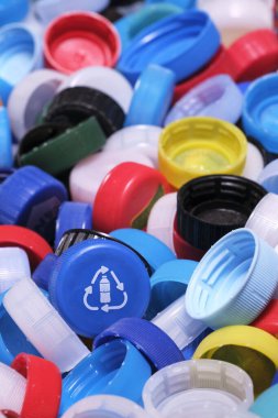 Geniş açılı, yakın plan, çeşitli renklerde kullanılmış plastik şişe kapağı koleksiyonu. Plastik atık, çevre kirliliği, geri dönüşüm girişimleri için görsel metafor. Seçici odak