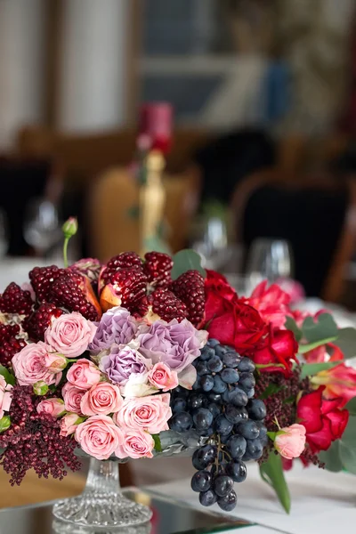 Ein Strauß roter und rosa Rosen, Pfingstrosen mit Trauben und Granatapfel-Nahaufnahme — Stockfoto