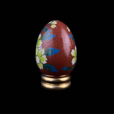 Red wooden Easter egg with floral patterns on isolated black background