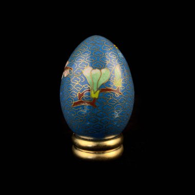 Blue wooden Easter egg with floral patterns on isolated black background