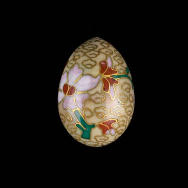 Yellow wooden Easter egg with floral patterns on isolated black background