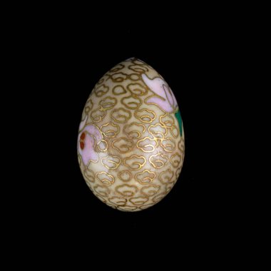 Yellow wooden Easter egg with floral patterns on isolated black background