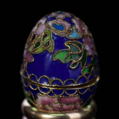 Metalik paskalya yumurtası, izole edilmiş siyah arka planda elle boyanmış desenler. Faberge yumurtası.
