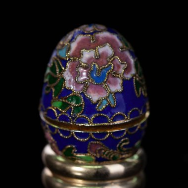 Metalik paskalya yumurtası, izole edilmiş siyah arka planda elle boyanmış desenler. Faberge yumurtası.