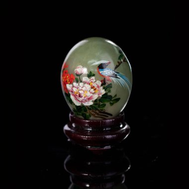 stone easter egg with hand painted beautiful birds on isolated black background