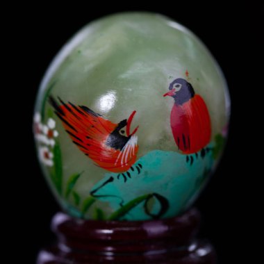 stone easter egg with hand painted beautiful birds on isolated black backgroundstone 