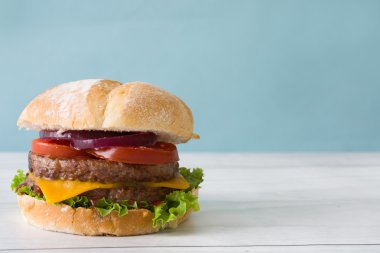 Kaşar peyniri, domates, marul, soğan ile lezzetli burger. Mavi arka plan