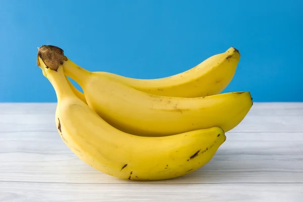 Banana on a white wooden table and blue background — Stock Photo, Image