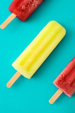 Mavi arka plan üzerinde çilek ve limon popsicles
