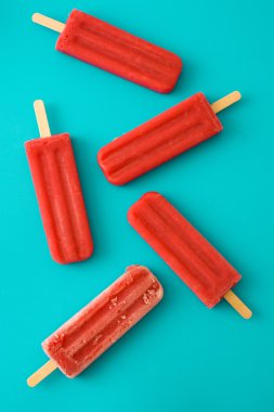 Mavi arka plan üzerinde çilek ve limon popsicles