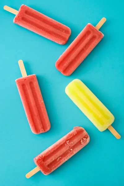 Mavi arka plan üzerinde çilek ve limon popsicles