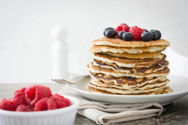 stock image Pancakes with blueberries and raspberries on rustic wood