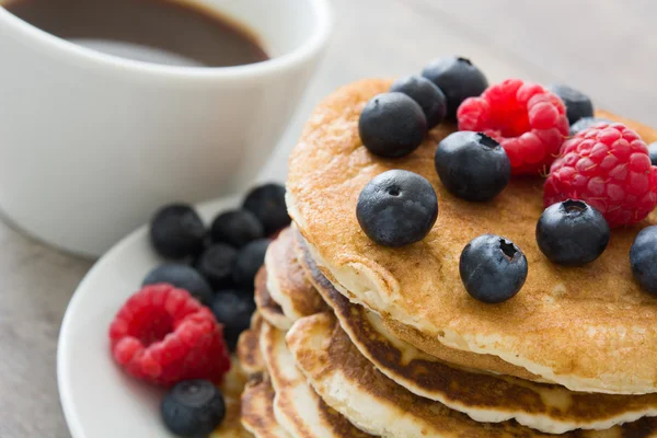 Pancakes with blueberries and raspberries on rustic wood — Stock Photo, Image