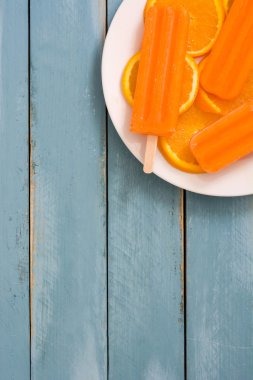 Mavi ahşap arka plan üzerinde turuncu çubuklu dondurmayı