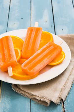 Mavi ahşap arka plan üzerinde turuncu çubuklu dondurmayı