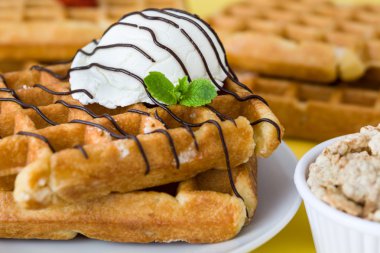 Waffle çikolata sosu, dondurma ve Sarı zemin üzerine rustik ahşap nane