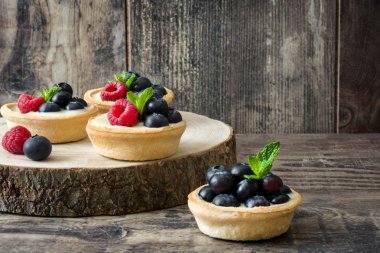 Ahududu ve ağaç gövdesi üzerinde yaban mersini ile lezzetli tartlets