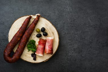 İspanyol serrano jambonu, zeytin ve sosis arduvaz arka plan üzerinde