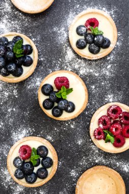 Ahududu ve arduvaz arka plan üzerinde yaban mersini ile lezzetli tartlets