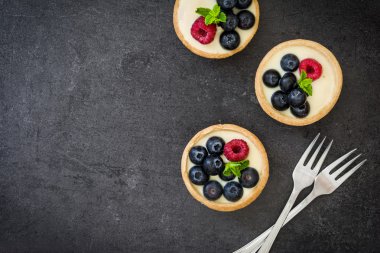 Ahududu ve arduvaz arka plan üzerinde yaban mersini ile lezzetli tartlets