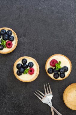 Ahududu ve arduvaz arka plan üzerinde yaban mersini ile lezzetli tartlets