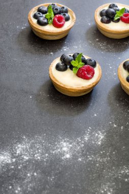 Ahududu ve arduvaz arka plan üzerinde yaban mersini ile lezzetli tartlets