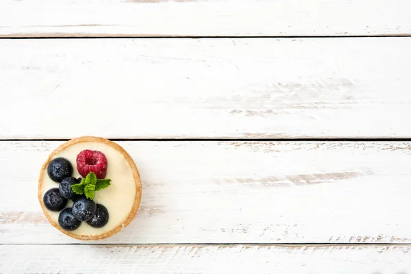 Délicieux tartelette aux framboises et aux bleuets sur une table en bois blanc — Photo