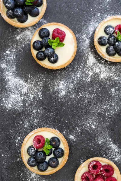 Deliciosas tartaletas con frambuesas y arándanos sobre fondo de pizarra —  Fotos de Stock