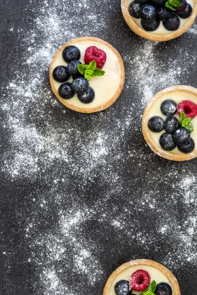 Deliciosas tartaletas con frambuesas y arándanos sobre fondo de pizarra —  Fotos de Stock