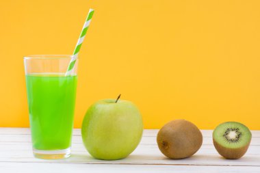 Apple ve kivi Beyaz ahşap masa ve sarı arka plan ile yeşil smoothie