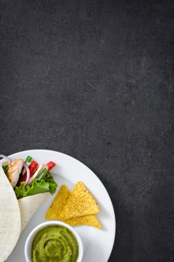 Meksika tavuk fajitas biber marul ve soğan, cips ve guacamole arduvaz arka plan üzerinde