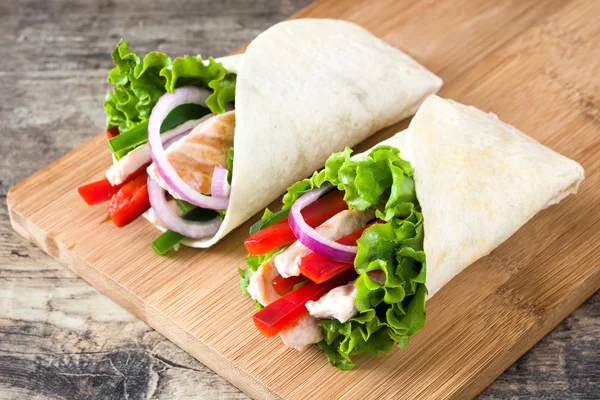 Fajitas mexicanas de pollo con pimientos lechuga y cebolla sobre una mesa rústica de madera —  Fotos de Stock