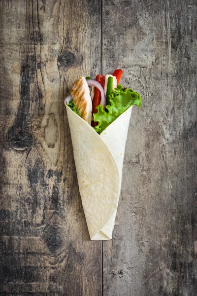 Fajita de pollo mexicano con pimientos lechuga y cebolla sobre una mesa rústica de madera —  Fotos de Stock