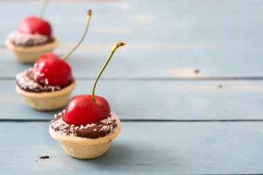 Bir kiraz ve Hindistan cevizi ahşap bir masa ile lezzetli çikolata tartlets