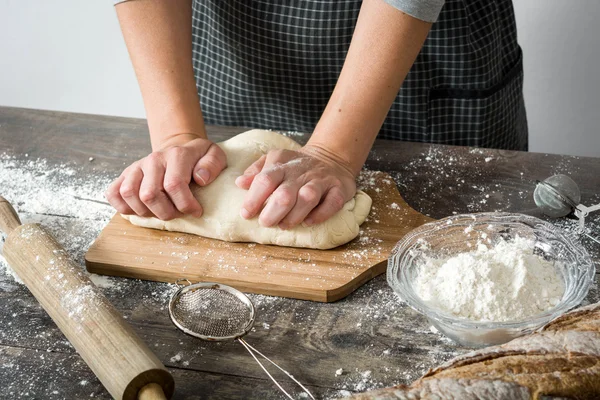 Mujer haciendo pan con la mano sobre la mesa de madera — Foto de Stock