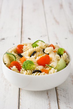 Beyaz ahşap bir masa üzerinde bir kapta makarna salatası