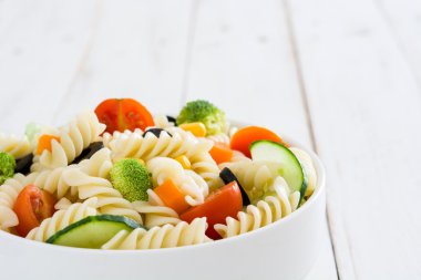 Beyaz ahşap bir masa üzerinde bir kapta makarna salatası