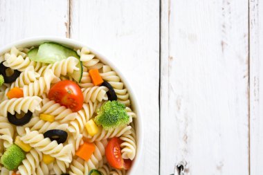 Beyaz ahşap masa üzerinde bir kapta makarna salatası