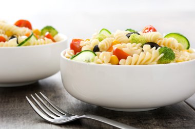 Rustik ahşap masa üzerinde bir kapta makarna salatası