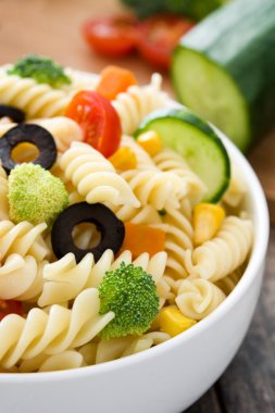 Rustik ahşap bir masa üzerinde bir kapta makarna salatası