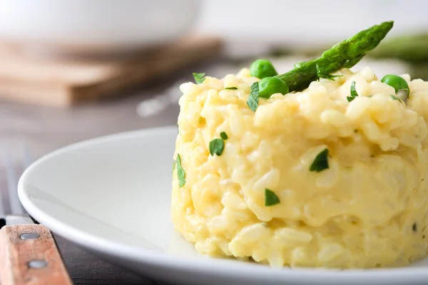 Risotto con espárragos, perejil y guisantes sobre una mesa rústica de madera —  Fotos de Stock