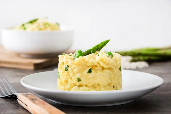 Risotto con espárragos, perejil y guisantes sobre una mesa rústica de madera —  Fotos de Stock