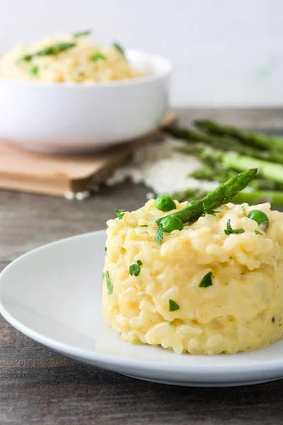 Risotto con espárragos, perejil y guisantes sobre una mesa rústica de madera —  Fotos de Stock