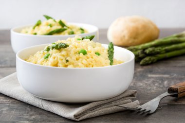Risotto ile kuşkonmaz, maydanoz ve rustik ahşap bir masa üzerinde bir kase bezelye